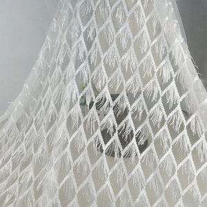 May include: White fabric with a diamond pattern and fringe trim. The fabric is sheer and delicate.