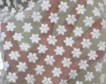 May include: White sheer fabric with a delicate floral pattern. The fabric is embroidered with small white flowers.