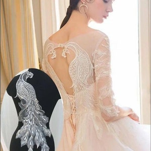 Peut inclure: Tissu de dentelle blanche avec un motif de paon. Le tissu est délicat et complexe, avec une finition chatoyante. Il est parfait pour ajouter une touche d'élégance à tout projet.