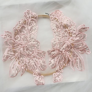 Op de afbeelding: Twee roze bloemvormige kantenapplicaties met pailletten. De applicaties zijn delicaat en ingewikkeld, met een bloemmotief. Ze zijn perfect om een ​​toets van elegantie aan elk project toe te voegen.