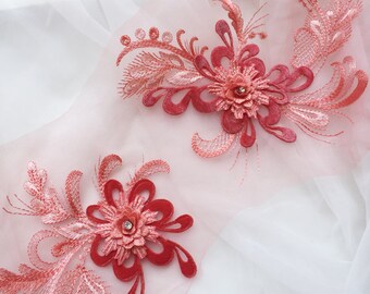 May include: Two coral pink floral appliques with a rhinestone center on a sheer white fabric. The appliques are made of lace and velvet.