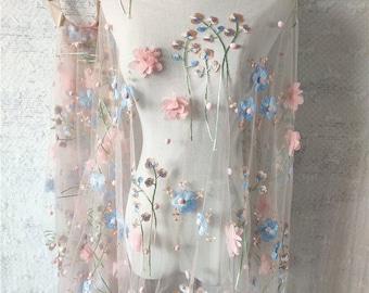 May include: Pink and blue floral embroidered tulle fabric with 3D flowers. The fabric is sheer and delicate, ideal for crafting and sewing projects.