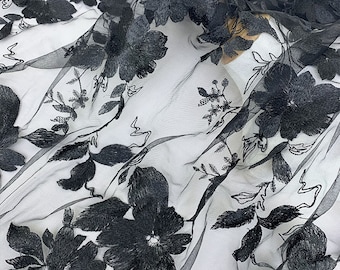 May include: Black floral embroidery on sheer white fabric. The embroidery is raised and has a 3D effect. The fabric is delicate and lightweight.