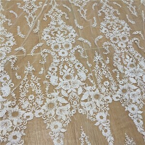 May include: White floral lace fabric with a delicate pattern. The lace is on a sheer mesh background.