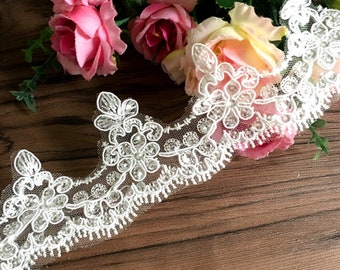 May include: White beaded lace trim with a floral design. The lace is delicate and has a soft, flowing texture.