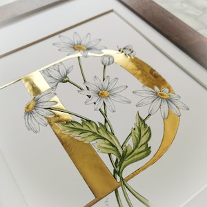 Estampado D de margaritas con hojas de oro aplicadas a mano. Una letra D dorada con margaritas entrelazadas y un abejorro. Hermoso para una habitación infantil o de bebé.