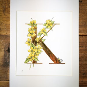 K es de Kerria, impresión giclée iluminada a mano. Una letra K dorada con Kerria y un abejorro. El oro se aplica a mano a cada impresión.