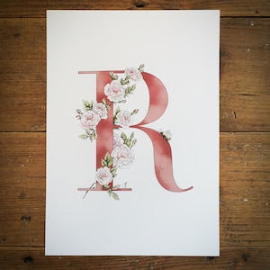 R de Rosa, letra con forma de flor. Una inicial R azul o rosa con rosas rosa pálido entrelazadas y un abejorro. Preciosa para una habitación infantil.