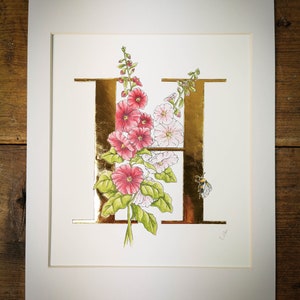 H is for Hollyhocks Impresión giclée con hoja de oro de 23,5 quilates aplicada a mano. Una letra H dorada con malvarrosas y un abejorro.