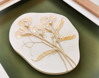 Sweetpeas fossil flower. Gold plaster cast flower art. A unique, one of a kind artwork with golden sweetpeas in a box frame on a green back.