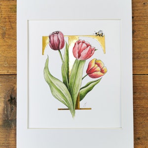 Estampado T de tulipanes con oro de 23,5 quilates aplicado a mano. Una letra T dorada con tulipanes entrelazados y un abejorro. Hermoso en una habitación infantil.