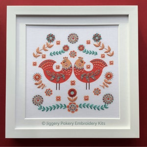 Completed bird embroidery mounted and shown in a square white frame.