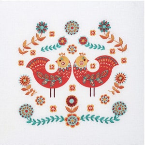 Folk art embroidery kit showing two red Scandi style birds decorated with simple embroidery stitches, surrounded by embroidered flowers in teal, red and apricot.
