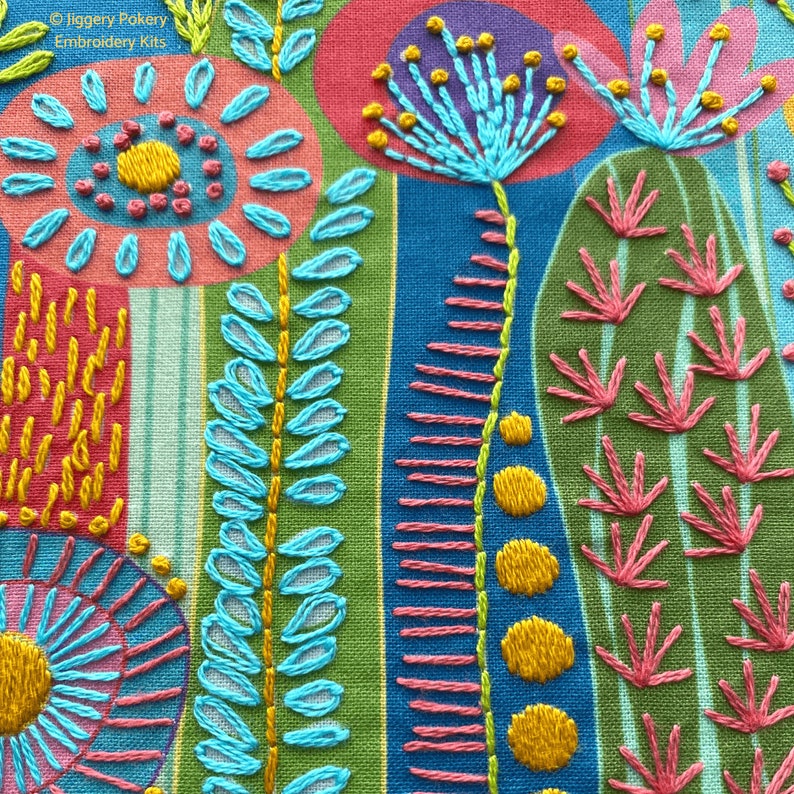 A close-up of embroidery stitches used on the cactus embroidery design. DMC threads in bright pink, blue, green and yellow are used.