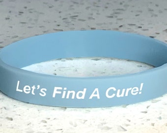 May include: A light blue silicone wristband with the text "Let's Find A Cure!" in white.