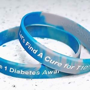 May include: Two blue and gray silicone wristbands with white text. The top band reads "Let's Find A Cure for T1D!" and the bottom band reads "Type 1 Diabetes Awareness".
