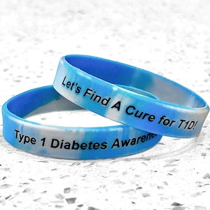 May include: Two blue and white tie-dye silicone wristbands with the text "Let's Find A Cure for T1D!" and "Type 1 Diabetes Awareness" printed in black.