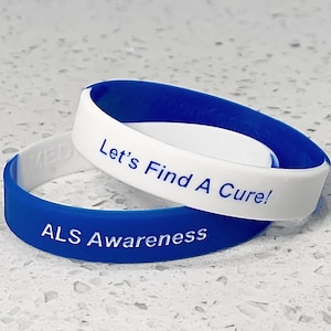 May include: Two blue and white silicone wristbands. The top band is white with blue lettering that reads "Let's Find A Cure!" The bottom band is blue with white lettering that reads "ALS Awareness".