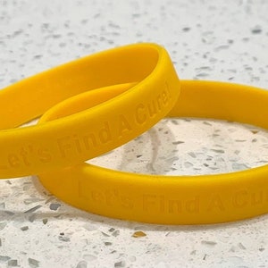 May include: Two yellow rubber bracelets with the text "Let's Find A Cure!" embossed on them.