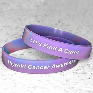 May include: Two purple and blue silicone wristbands with white text. The top band reads "Let's Find A Cure!" and the bottom band reads "Thyroid Cancer Awareness".