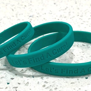May include: Three teal silicone wristbands with the text "Let's Find A Cure!" embossed on each.