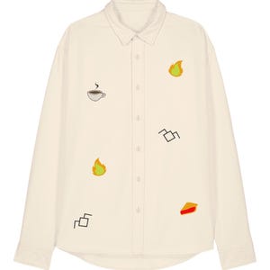 Può includere: Camicia color crema con bottoni e maniche lunghe. La camicia presenta disegni ricamati tra cui una tazza di caffè, fiamme, forme geometriche e una fetta di torta. La camicia ha un colletto classico e polsini con bottoni.