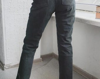 May include: Dark gray denim pants with two back pockets and a small logo on the right pocket. The pants have a straight leg cut and are worn with red sandals.