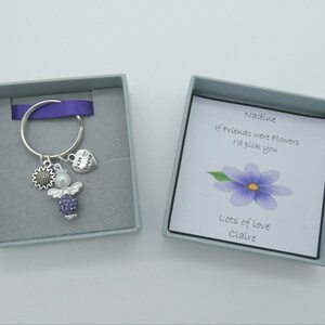 May include: A small gift box with a purple angel keychain inside. The box has a card that reads "Nadine, If friends were flowers I'd pick you. Lots of love, Claire."