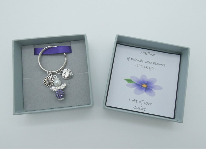 May include: A small gift box with a purple angel keychain inside. The box has a card that reads "Nadine, If friends were flowers I'd pick you. Lots of love, Claire."