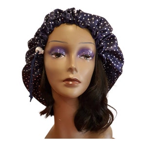 May include: A navy blue satin sleep cap with white polka dots. The cap has a drawstring closure and is designed to protect hair while sleeping.
