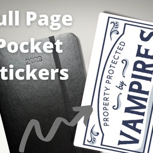 May include: A white sticker with blue text that reads "PROPERTY PROTECTED by VAMPIRES". The sticker is on a black leather-bound pocket planner with the year 2023 embossed on the cover.