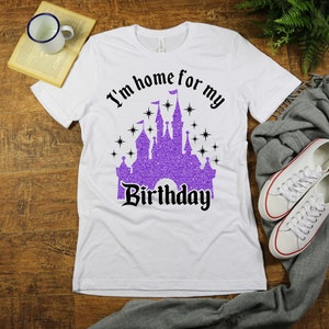 May include: White t-shirt with a purple glitter castle graphic and the text "I'm home for my birthday".