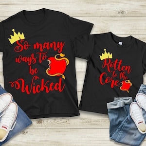 May include: Two black t-shirts with a red apple and crown graphic. The larger shirt says "So many ways to be wicked". The smaller shirt says "Rotten to the core".