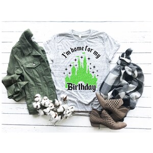 May include: A gray t-shirt with a green glitter castle graphic and the text "I'm home for my birthday".
