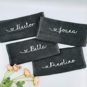 May include: Four black towels with white embroidered hearts and names: Hector, Joana, Bella, and Pinolino.
