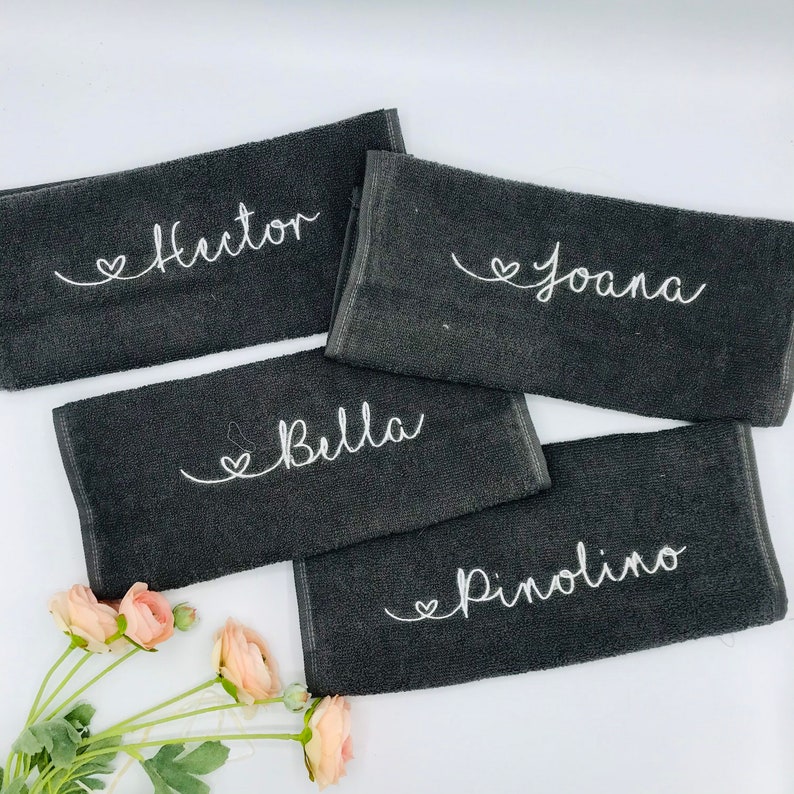 May include: Four black towels with white embroidered hearts and names: Hector, Joana, Bella, and Pinolino.