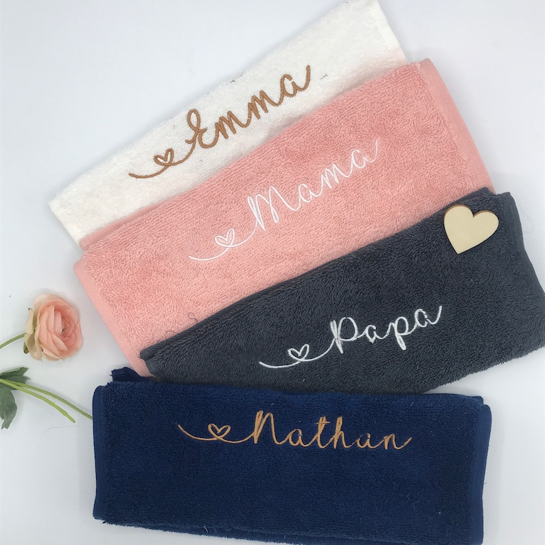 May include: Four towels with embroidered names and hearts. The towels are white, pink, gray, and navy blue. The names are Emma, Mama, Papa, and Nathan.