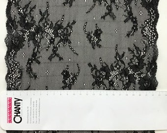 May include: Black lace fabric with a floral pattern. The lace is delicate and has a scalloped edge. The fabric is measured in inches.