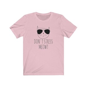 May include: Pink t-shirt with a black and white illustration of a cat wearing sunglasses and the text "Don't Stress Meowt"