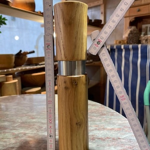 May include: A wooden pepper mill with a silver band. The mill is approximately 18 inches tall.