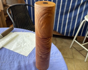Könnte beinhalten: Ein Salz- und Pfeffermühlen-Set aus Holz mit natürlicher Holzoptik. Die Mühle besteht aus zwei Teilen, einem Ober- und einem Unterteil, die miteinander verschraubt werden. Das Oberteil hat einen schwarzen Metallknopf zum Mahlen.