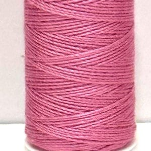 May include: A spool of pink cotton thread labeled "Cotton Petites Art 1" and "Staple Cotton." The thread is a vibrant pink color, and the spool has the number "46" printed on it. The number "T161" is printed on the bottom.