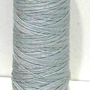 May include: A spool of light gray thread with white end caps. The thread is tightly wound, and the spool has the text "#309 50M 1" and "T330" printed on it.