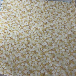 May include: A fabric swatch with a white background and a pattern of small, light brown and yellow circles.