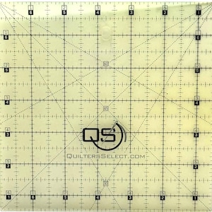 May include: A clear, transparent quilting ruler with black grid lines, diagonal markings, and numbered increments. The ruler features the text "QS" inside a circle and "QUILTERSSELECT.COM". The grid is marked with numbers and dashed lines for precise measurements.