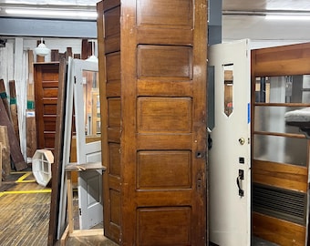 May include: A vintage wooden door with six raised panels. The door is made of dark wood and has a natural finish. The door is in good condition and has a classic design.