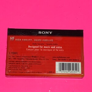 May include: A red and black Sony HF High Fidelity audio cassette tape. The packaging includes text in English and French, with details about recording time and warranty information. The cassette is designed for music and voice.
