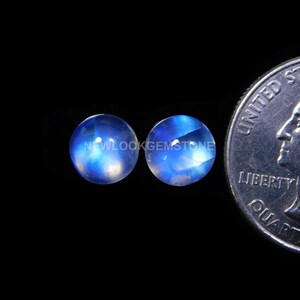 May include: Two round, blue moonstone cabochons, each approximately the size of a US quarter.