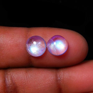 May include: Two round, iridescent moonstone cabochons with a blue and white sheen. The stones are approximately 10mm in diameter.