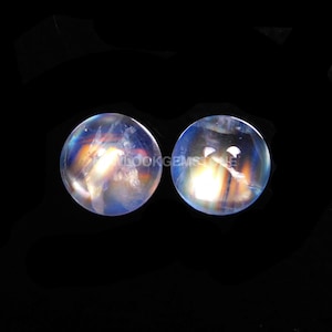 May include: Two iridescent rainbow moonstone spheres, each with a diameter of approximately 1 inch. The spheres are smooth and polished, with a translucent white color and a rainbow sheen.